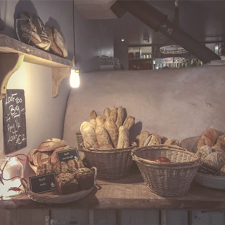 Baskets of bread and pastries on wooden shelves in a bakery