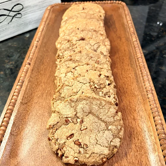 A row of brown butter pecan cookies on a wooden serving tray